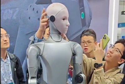 The Unitree H2 humanoid robot being observed up close at IROS 2025.