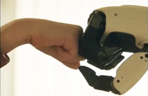 Nahaufnahme der Hand des LG CLOiD Roboters, die einer menschlichen Hand einen Fauststoß gibt, als Symbol für die Mensch-Roboter-Interaktion.
