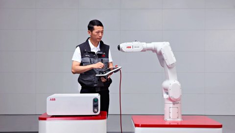 Ein Ingenieur programmiert einen ABB IRB 1200 Roboterarm mit einem Tablet-Controller.